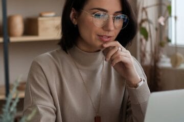 A lady with a beige t-shirt sitting with her laptop